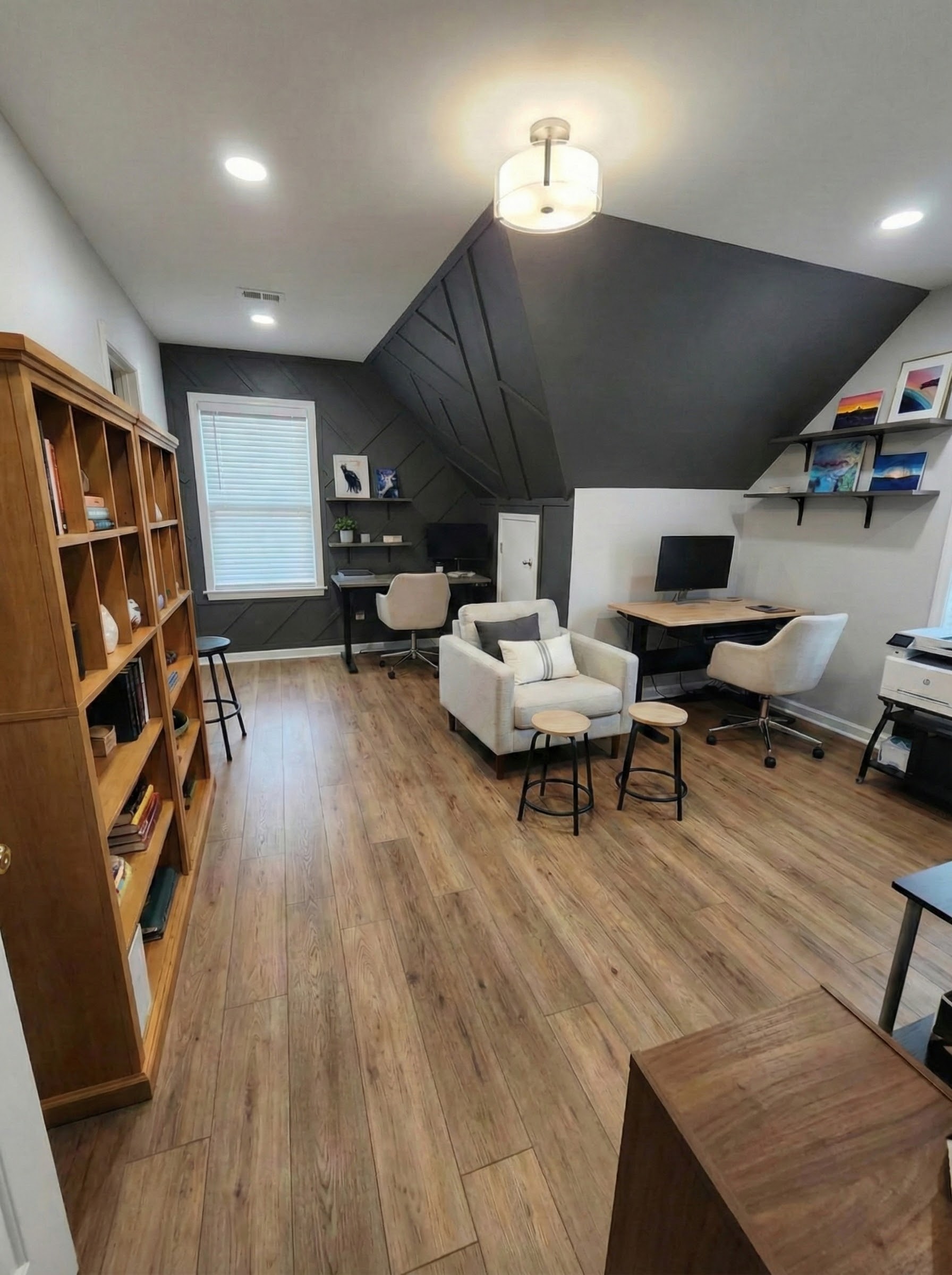 Interior staircase after renovation with black metal railing, plank flooring, and a pendant chandelier