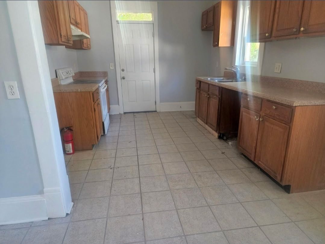 Dated kitchen with oak cabinetry and tile flooring before renovation