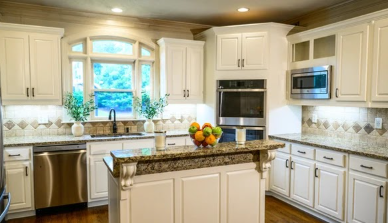 Refinished white kitchen cabinetry with granite countertops and stainless appliances