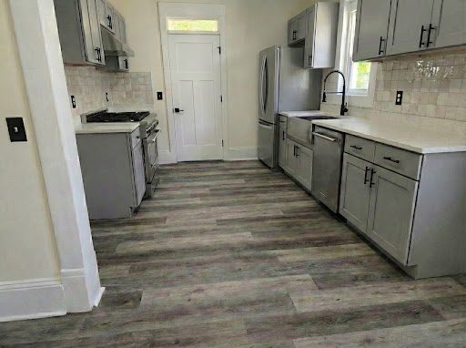 Refreshed kitchen with light gray cabinetry, tile backsplash, and wood-look plank flooring